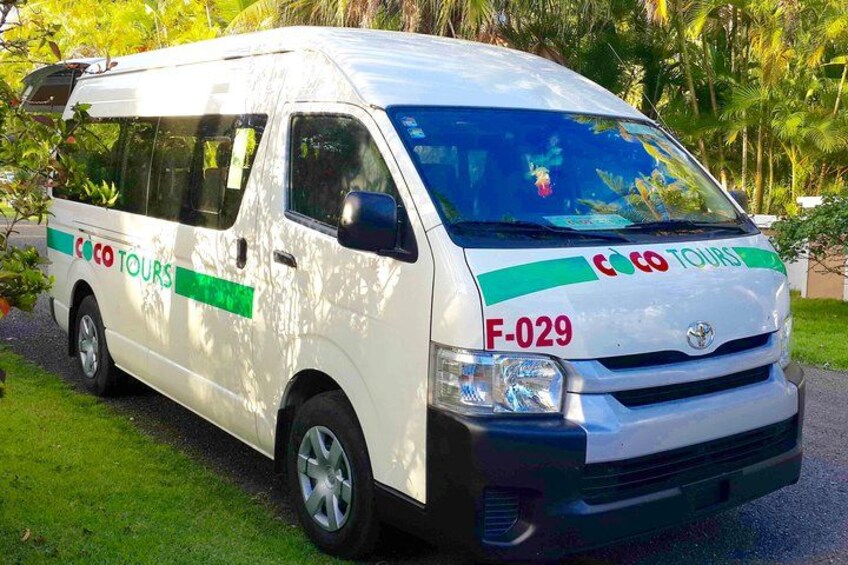 A white van with green and red text, parked on a grassy area with trees in the background. 1