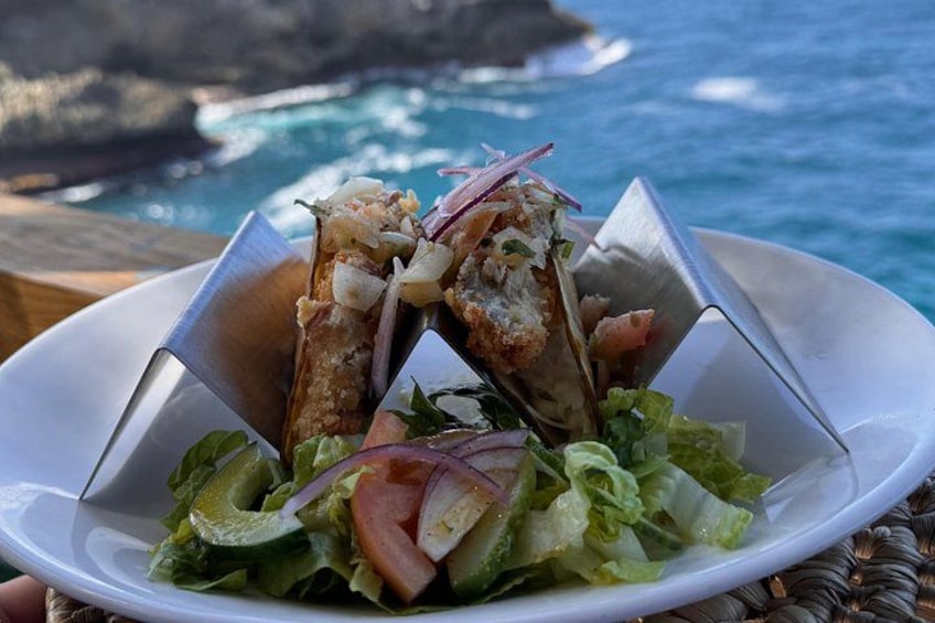 A seafood dish with a salad on a plate, set against a coastal backdrop. 4