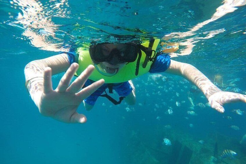 A person underwater, wearing a snorkel and fins, surrounded by fish. 3