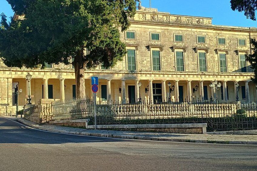 A historic building with a stone facade, green shutters, and a wrought iron fence. 2