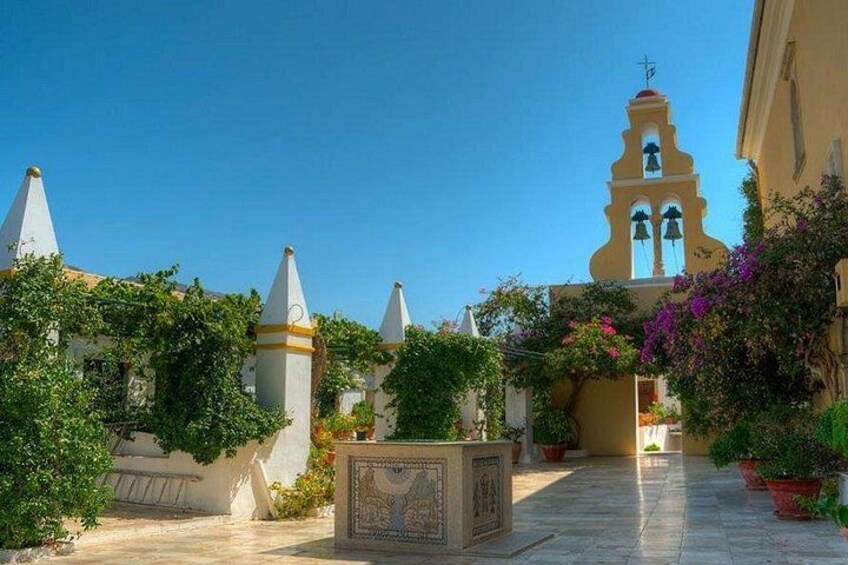 A courtyard with a bell tower, potted plants, and a tiled floor. 1