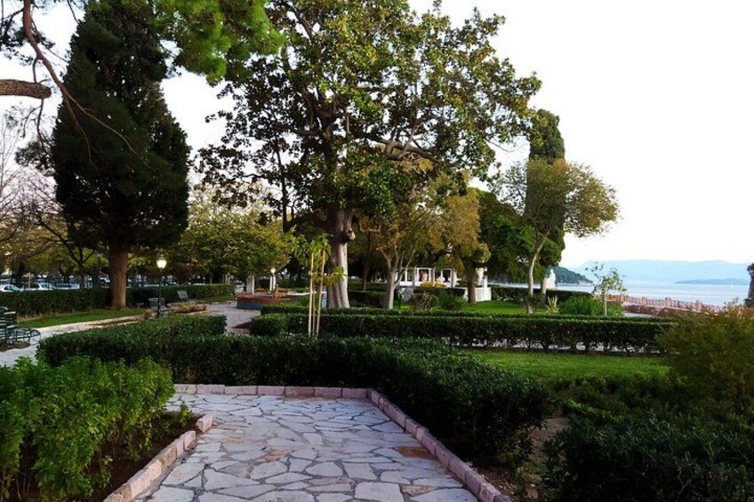 A stone pathway, lush greenery, and a view of the sea. 4