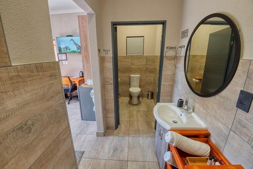 Un baño con tocador de madera, lavamanos, espejo e inodoro. 2