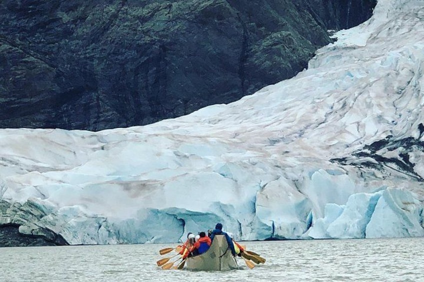 A kayak on calm water with a glacier in the background. 1