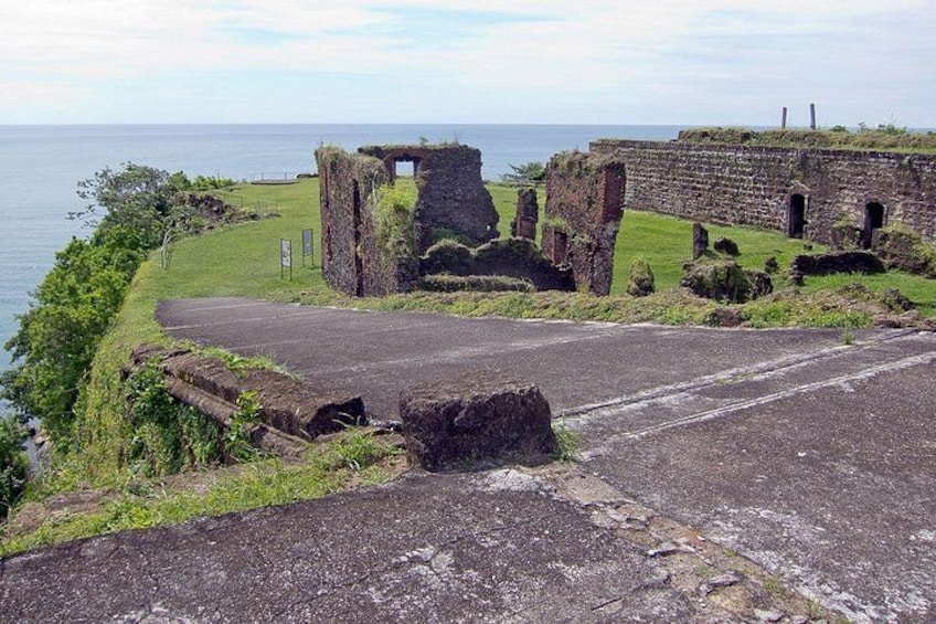 Ruinas costeras con vegetación abundante, un camino empedrado y un área cubierta de césped. 5