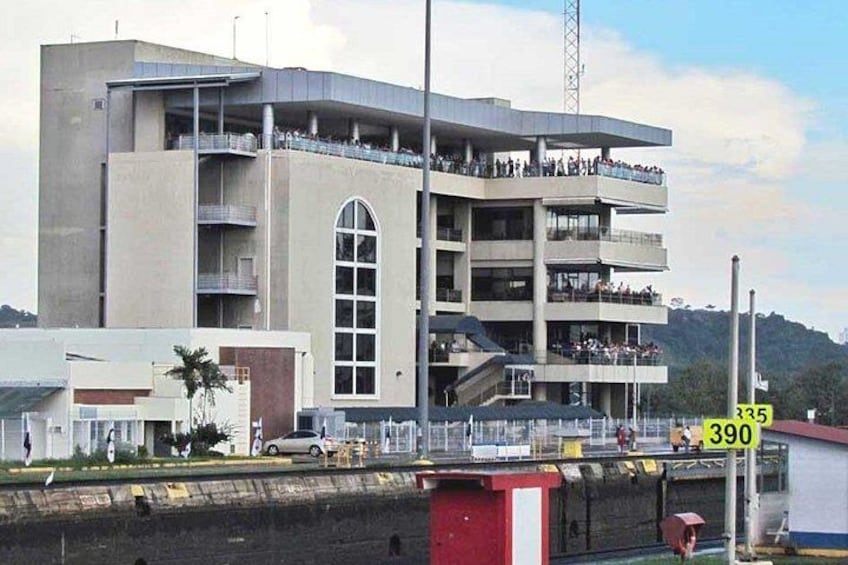 A multi-story building with balconies, a red and white structure in the foreground, and a sign with numbers 335 and 390. 5