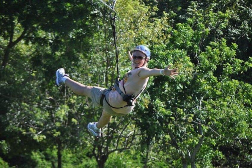 Una persona haciendo bungee jumping con arnés y equipo de seguridad, rodeada de abundante follaje verde. 2