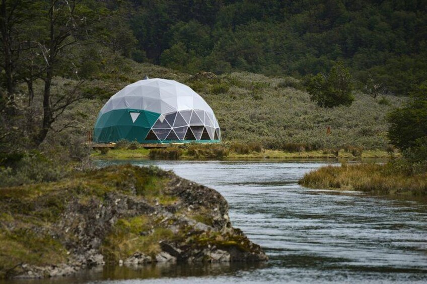 A geodesic dome structure near a river in a natural setting. 5