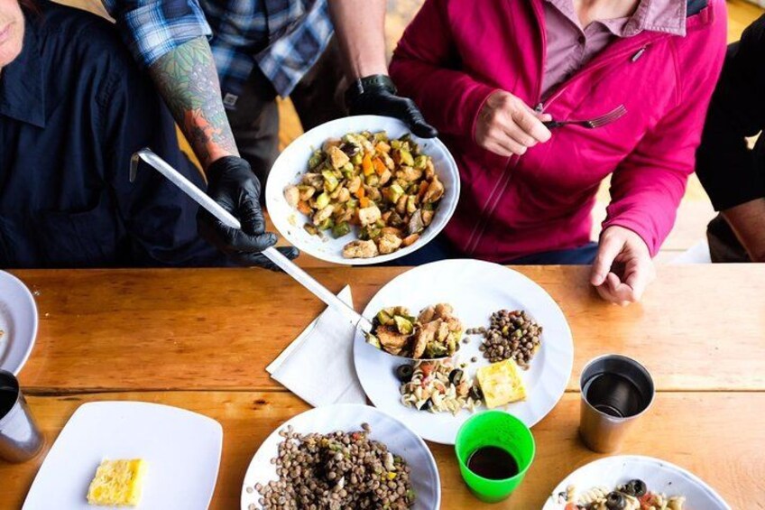 A group of people sitting around a wooden table with various dishes of food. 2