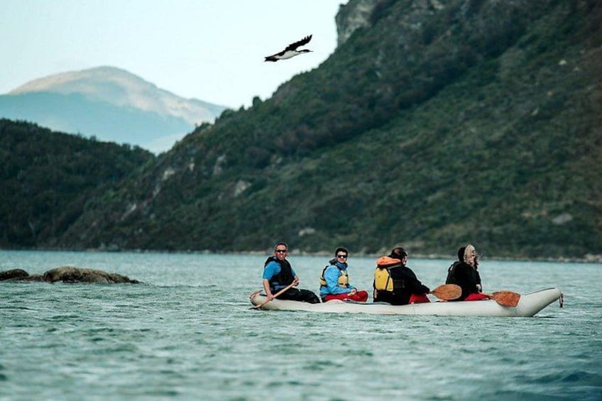 Cuatro personas en una canoa sobre aguas tranquilas, con montañas al fondo. 5
