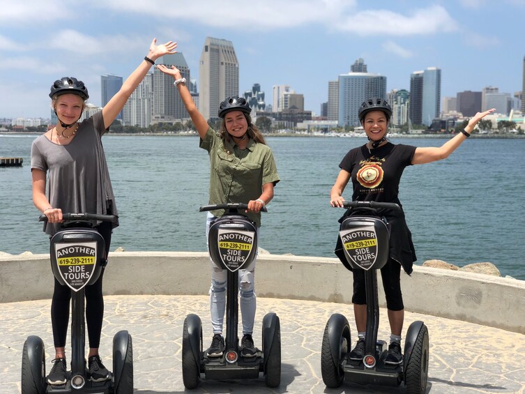 Three people on segways with a city skyline and water in the background. 5