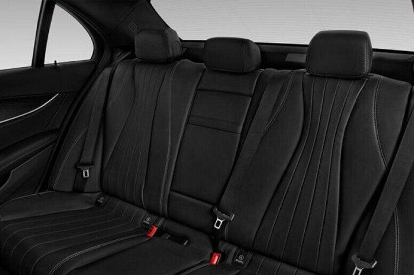 Das Innere eines Autos mit schwarzen Ledersitzen, Sicherheitsgurten und einer sichtbaren Gurtschnalle. 3