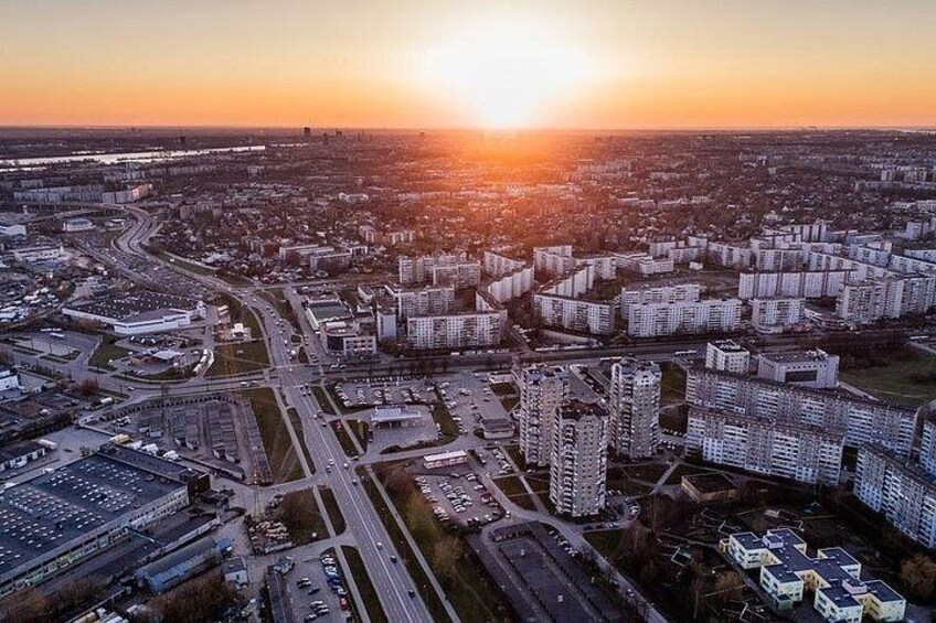 Eine Vogelperspektive auf eine Stadtlandschaft bei Sonnenuntergang, mit Hochhäusern, Straßen und einem Fluss im Hintergrund. 5