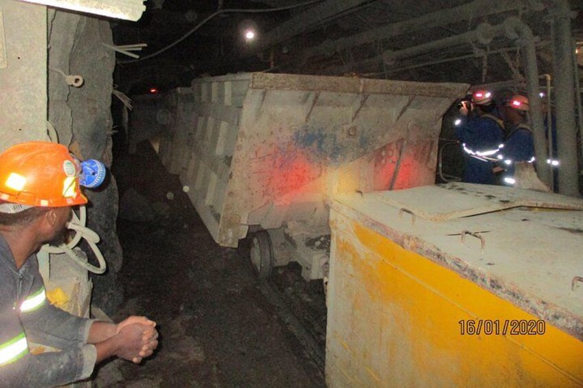A mining operation with workers, a large dump truck, and a conveyor belt. 4