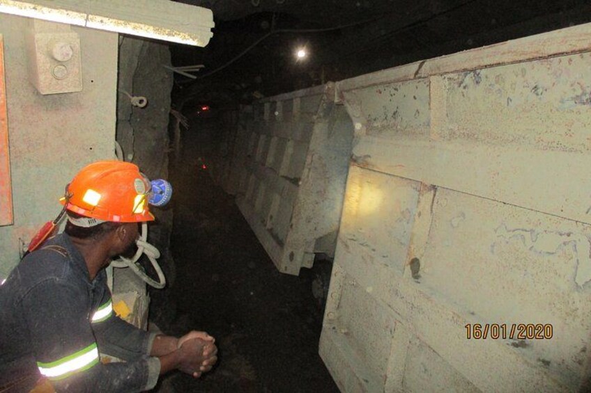 A person in a hard hat and safety vest inside a tunnel with concrete walls and a metal structure. 5