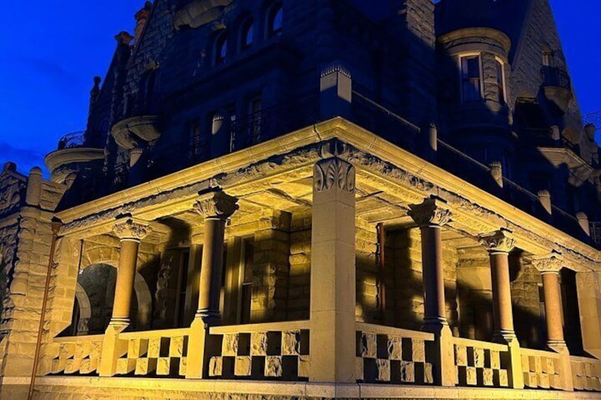 A grand building with ornate columns and a balcony, illuminated at dusk. 5