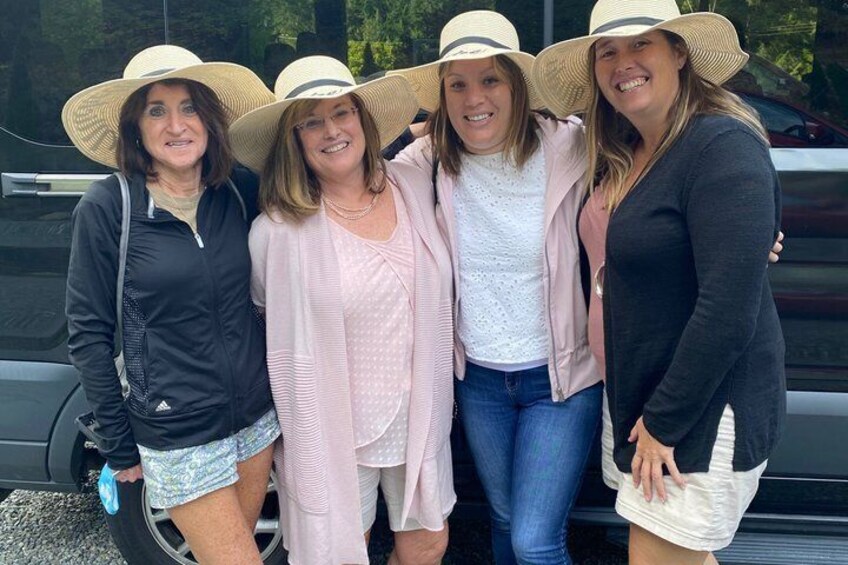 Four people standing in front of a vehicle, wearing hats and casual clothing. 3