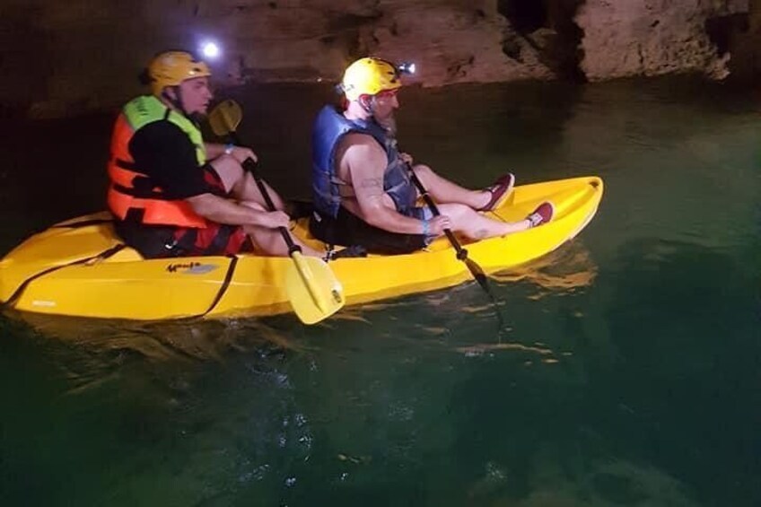 Deux personnes pratiquent le kayak dans un radeau jaune à l’intérieur d’une grotte. 1