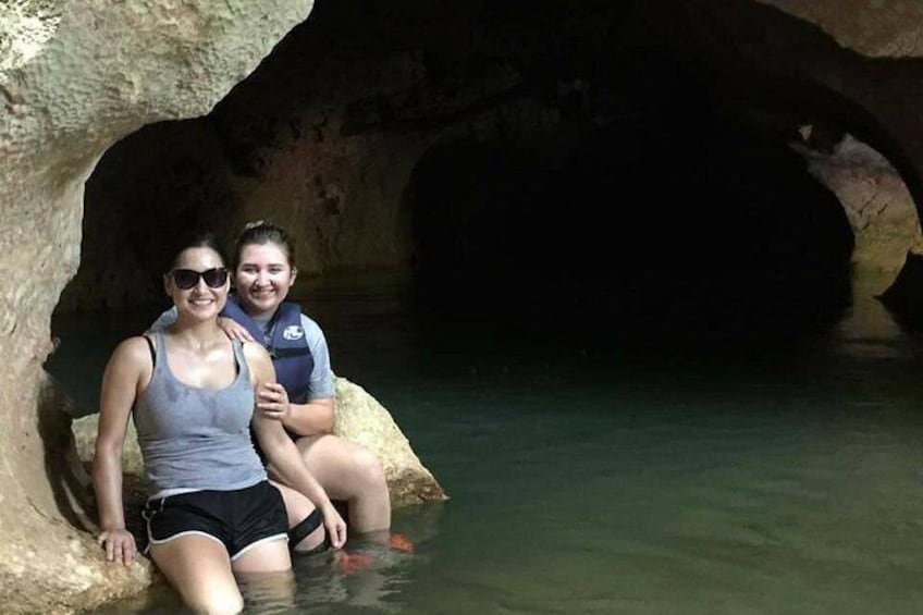 Dos personas sentadas sobre rocas en una cueva con agua. 4