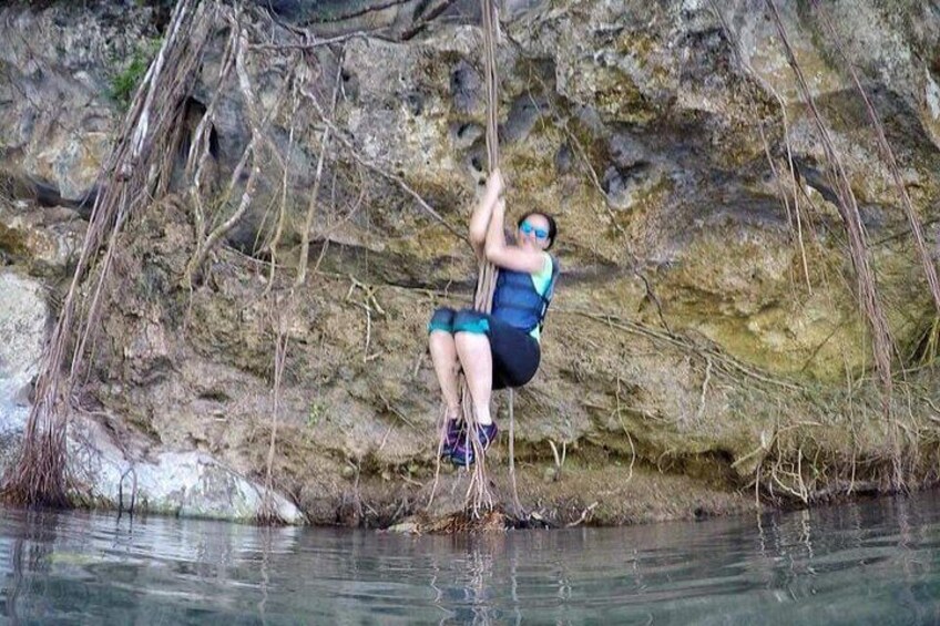 A person rappelling down a rocky cliff into a body of water. 2