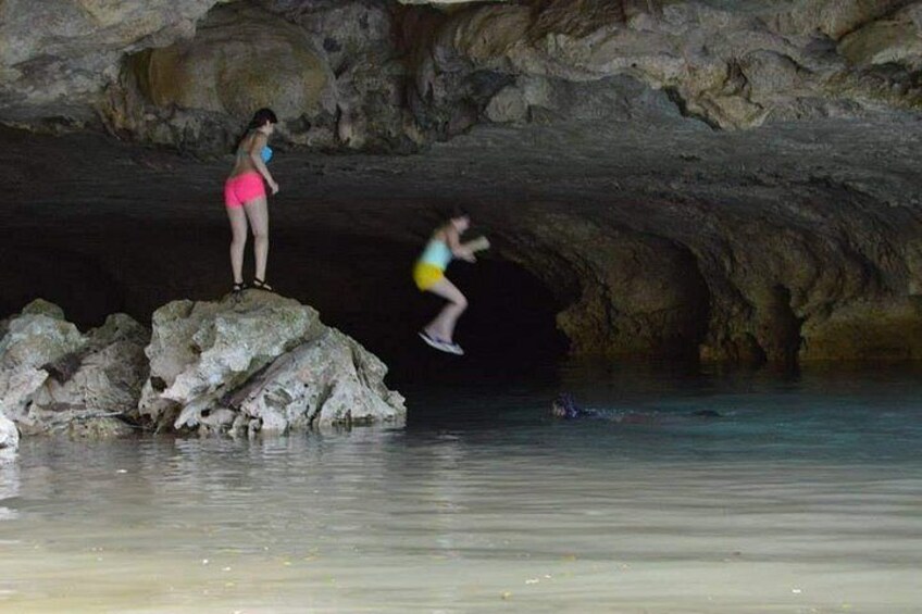 A cave with rocky formations and a person jumping into the water. 3