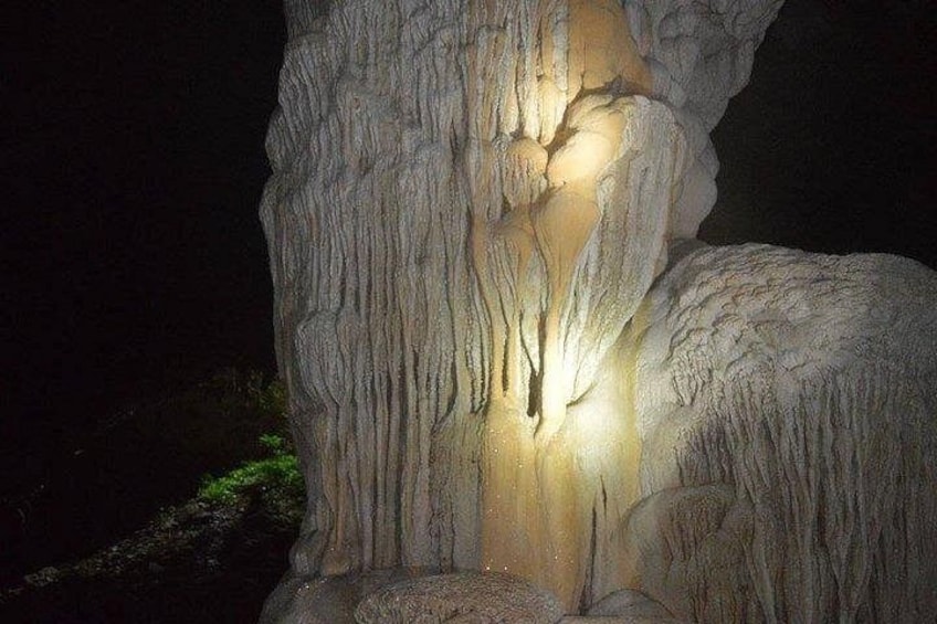 A large rock formation with intricate striations and a warm light source highlighting its texture. 2
