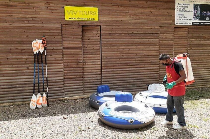 A person standing next to inflatable rafts and paddles against a wooden wall with a sign that reads 'VIV TOURS'. 2