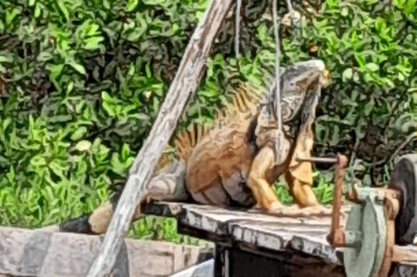 Una scultura in legno raffigura un dinosauro in un giardino. 2