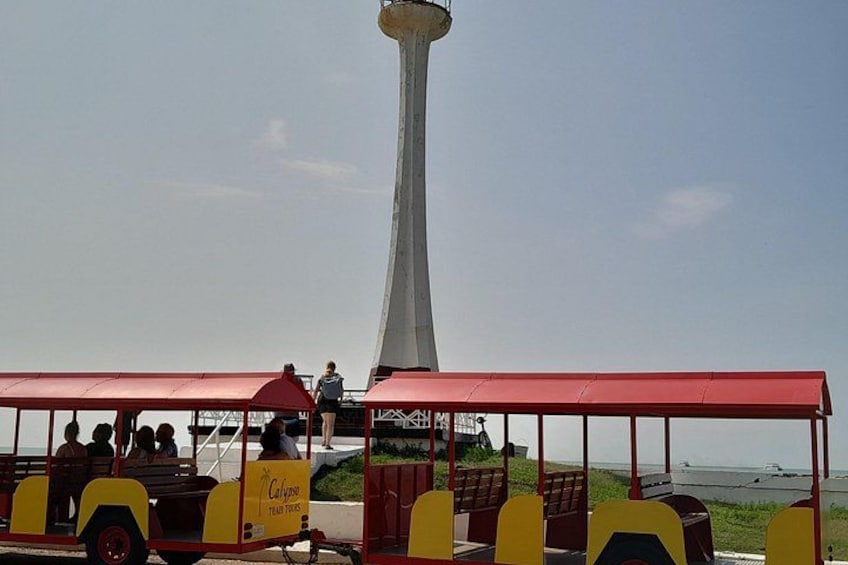 Un carrello rosso e giallo con passeggeri, un'alta torre bianca e una vista sulla costa. 4