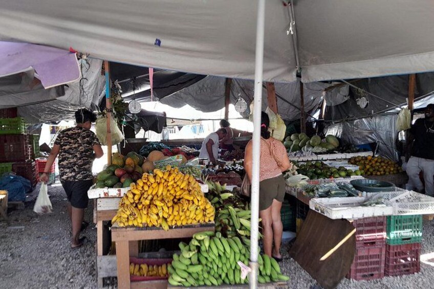 Un marché où l’on peut trouver une variété de fruits et de légumes, présentés sous une tente. 1