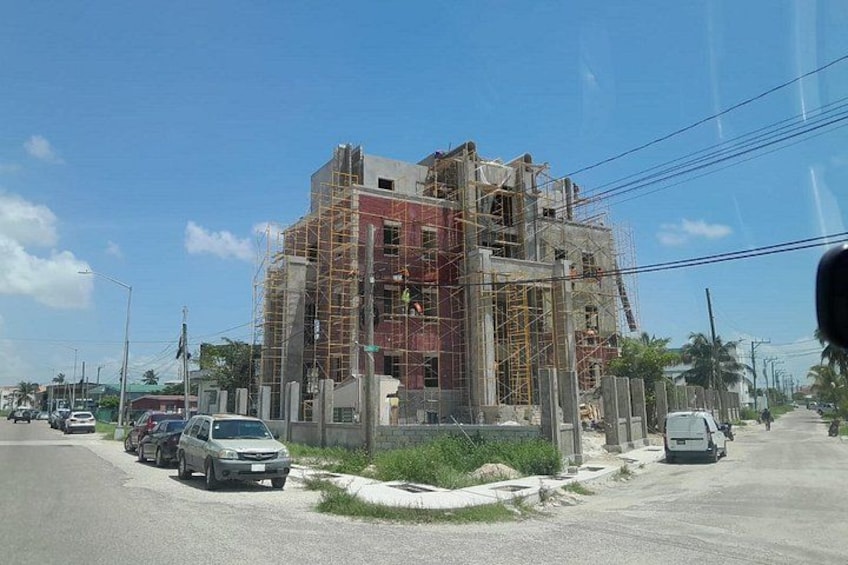 A building under construction with scaffolding, parked cars, and a clear sky. 2