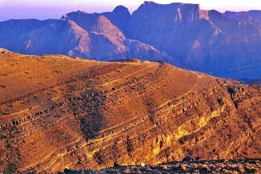 Een ruig berglandschap met gelaagde gesteenten en een heldere lucht. 4