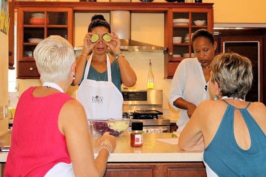 A group of people in a kitchen with a stove, cabinets, and a bottle on the counter. 3