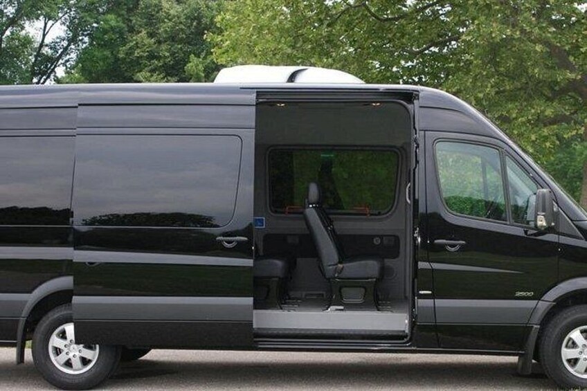 Una camioneta negra con la puerta lateral abierta, mostrando los asientos interiores y una persona en su interior. 5