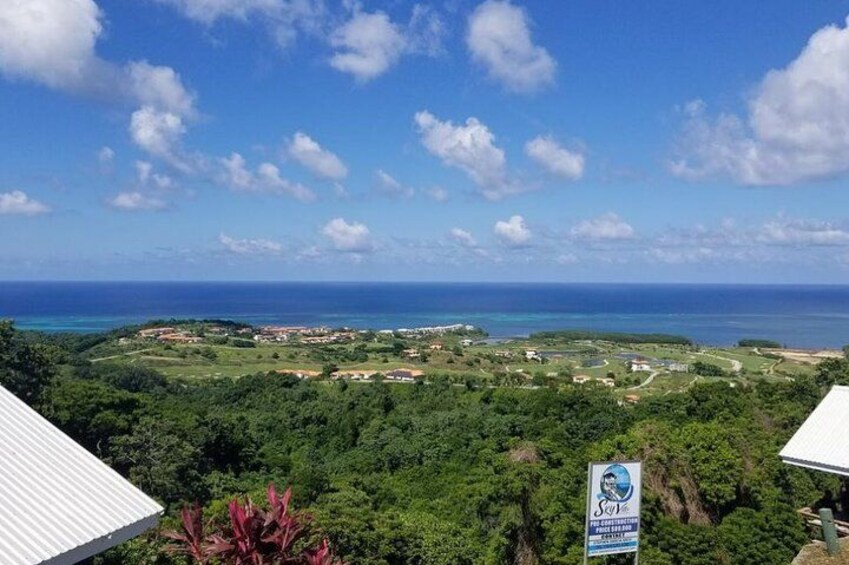 A coastal landscape with a view of the ocean, a signboard, and a lush green area. 2