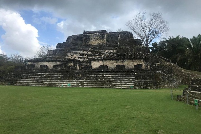 A large ancient pyramid with a grassy foreground and a cloudy sky. 1