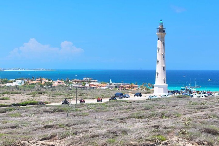 Una zona costiera con un faro, veicoli e edifici vicino alla riva. 5