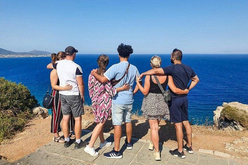 En gruppe mennesker står på en stien af sten og kigger ud over havet. 4