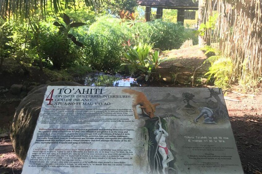 A sign with information about To'Ahiti, a god of the inland seas, in a garden setting. 2
