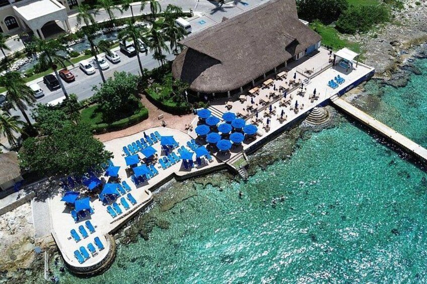 Una località turistica con area piscina, lettini e un edificio con tetto di paglia. 3