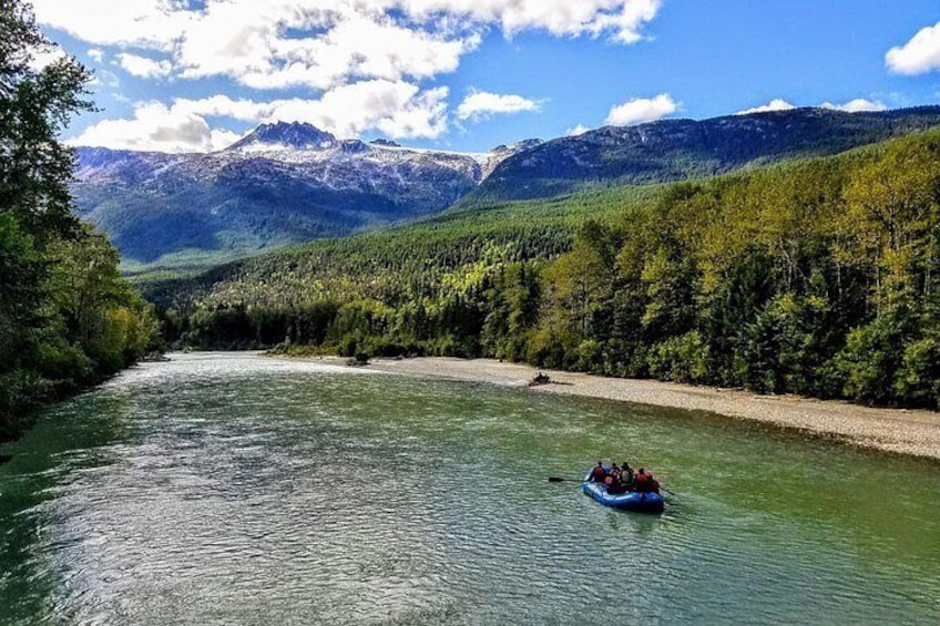 Un río con una balsa, rodeado de bosque y montañas. 2