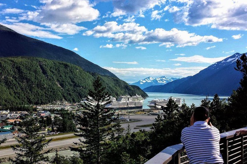 A person overlooking a coastal town with mountains, a body of water, and a cruise ship. 2