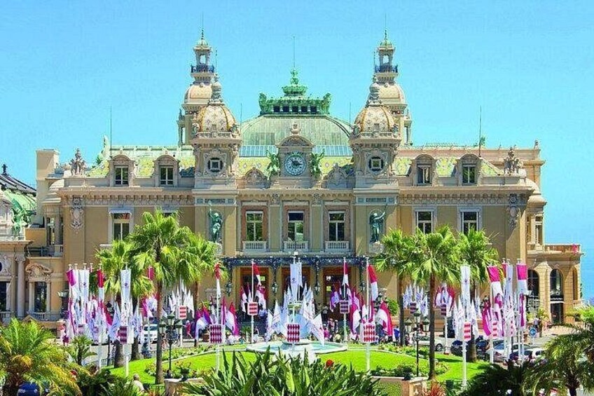 A grand building with a dome and two towers, surrounded by palm trees and flags. 5