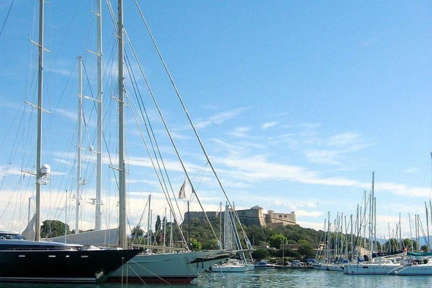 A marina with sailboats docked, a clear sky, and a castle in the background. 4