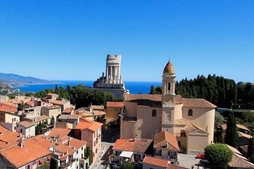 A coastal town with historic architecture, including a prominent tower and a church with a bell tower. 5