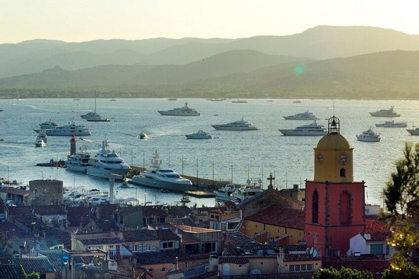 A harbor with multiple yachts and a prominent red bell tower. 2