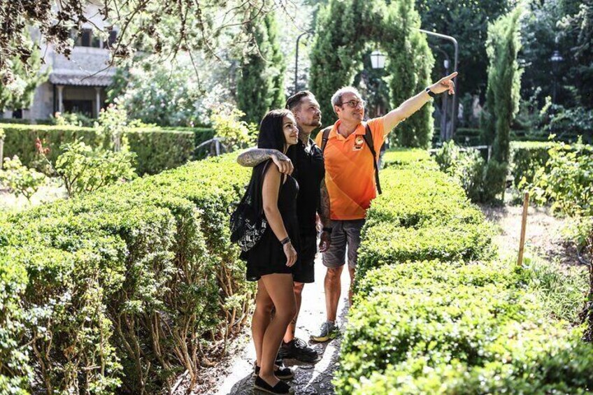 Tre personer som tar en selfie i en trädgård med välklippta häckar och träd. 1