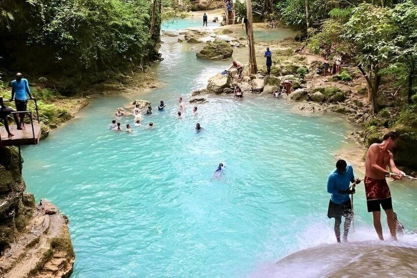 A natural hot spring with clear turquoise water surrounded by lush greenery. 5