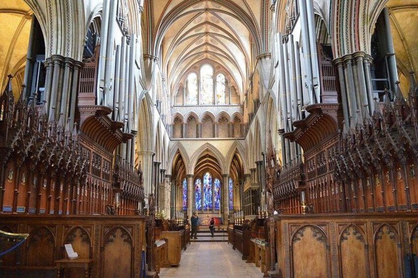 A cathedral interior with high vaulted ceilings, stained glass windows, and rows of wooden pews. 2