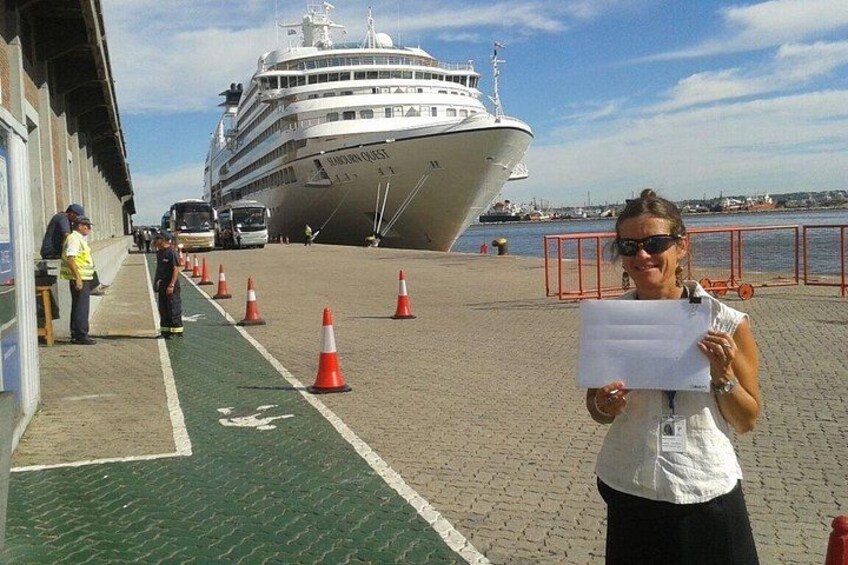 Ein Kreuzfahrtschiff liegt in einem Hafen vor Anker, eine Person hält ein Papier. 2